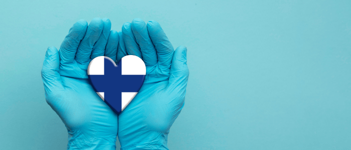 Pair of hands in medical latex gloves hold a heart painted with the flag of Finland, to represent the concept that the FinOMOP consortium uses OMOP CDM for RWD studies milestone