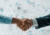 Two people shaking hands in front of a blurry background. One person is in a suit, one is in a shirt. They are only visible from their waist to their shoulders. To represent that Flatiron and NCCN to improve cancer outcomes using RWD.