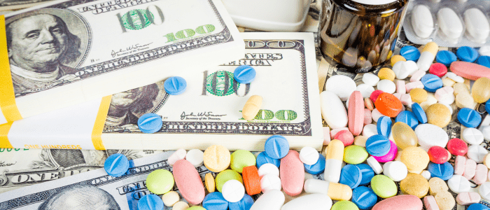 Various tablets and a bottle on top of stacks of US dollars. To represent that CMS releases draft guidance for second cycle of Medicare Drug Price Negotiation Program