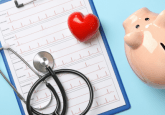A piggy bank, a stethoscope and a red plastic heart on top of a clipboard showing ECG results. To represent that IVI launches Phase II Project to address PCEI in healthcare.