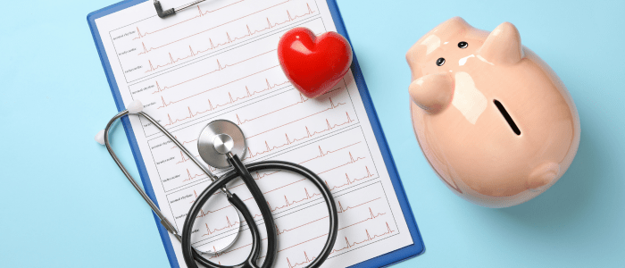 A piggy bank, a stethoscope and a red plastic heart on top of a clipboard showing ECG results. To represent that IVI launches Phase II Project to address PCEI in healthcare.